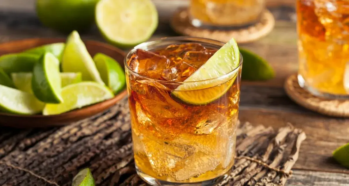 Idealny drink z rumem i lodem, ozdobiony plasterkiem limonki. Obok miseczka z kawałkami limonki, sugerująca, z czym pić rum.