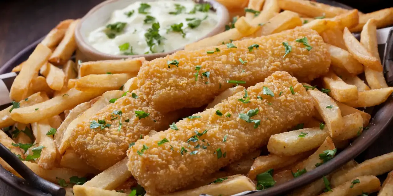 Knusprige Fischstäbchen mit Pommes und Dip. Perfekt paniert ohne Ei, garniert mit Petersilie. Ein Genuss für Groß und Klein.