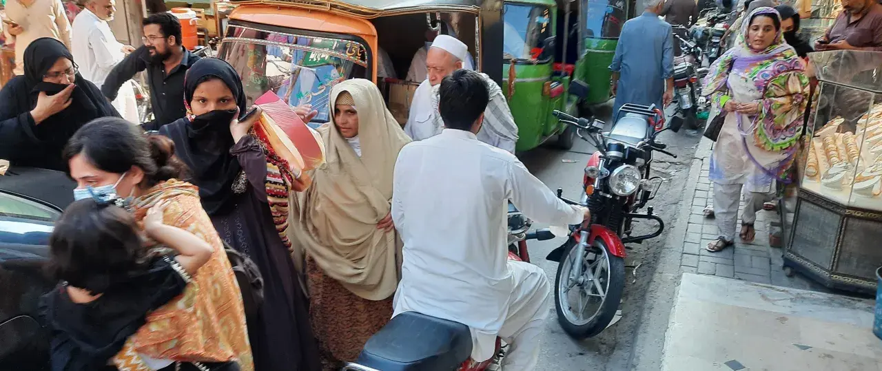Ludzie na ulicy w Pakistanie, wśród nich kobiety w hidżabach i dzieci. Czy pakistan jest bezpieczny? Tłum na targu, ruchliwa ulica.