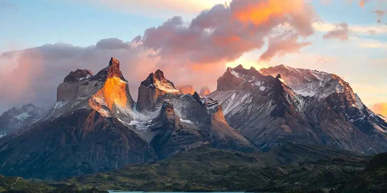 Wspaniała wycieczka do Chile! Słońce oświetla skaliste szczyty Torres del Paine, odbijając się w turkusowym jeziorze.