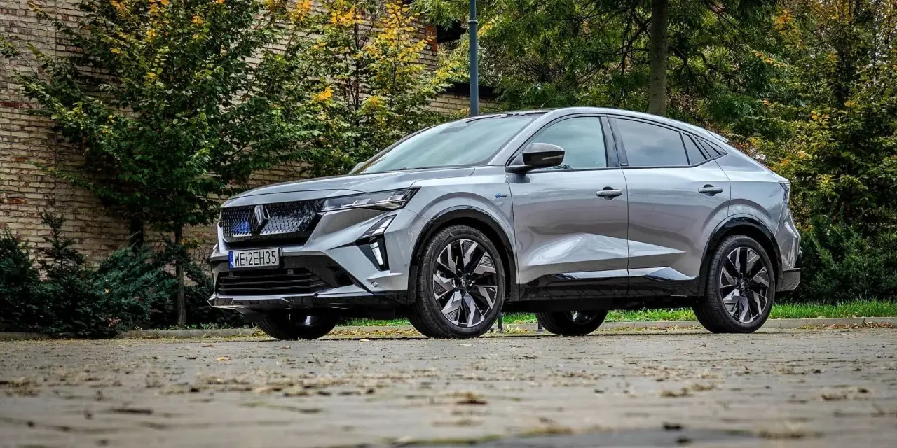 Nowy Renault Rafale, elegancki SUV coupe, prezentuje się na tle jesiennej zieleni i ceglanej ściany.