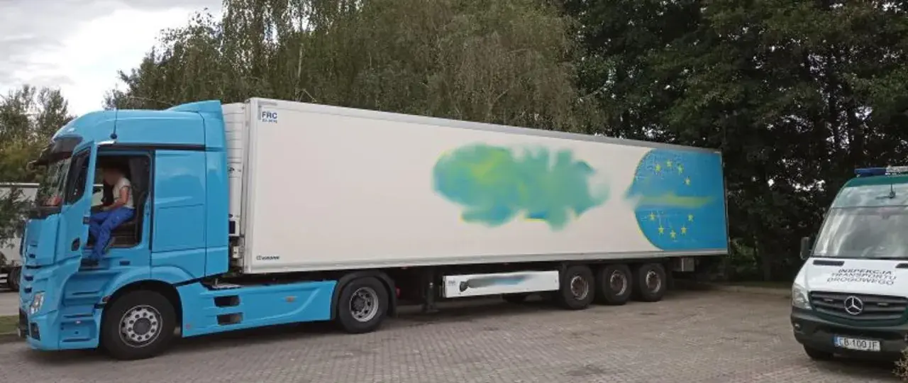 Niebieska ciężarówka z naczepą, na której widnieje symbol UE. Obok stoi biały bus inspekcji transportu drogowego. Certyfikat ATP potwierdza gotowość do przewozu.