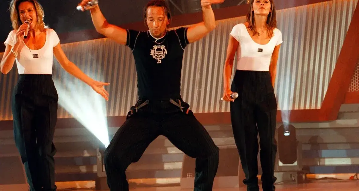Drei Künstler in Schwarz-Weiß-Outfits performen auf einer Bühne. Die Frau links singt, der Mann in der Mitte tanzt, die Frau rechts hält ein Mikrofon. Ein energiegeladener Moment für **dance & electronic** Musik.