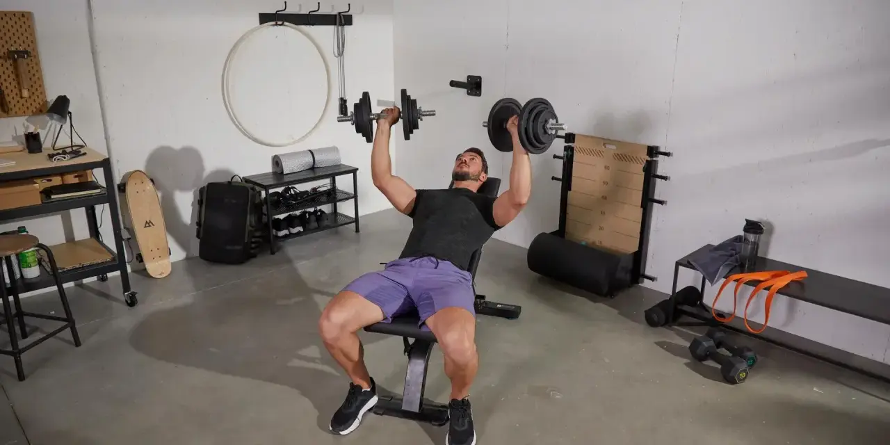 Homme faisant un exercice banc de musculation avec haltères.