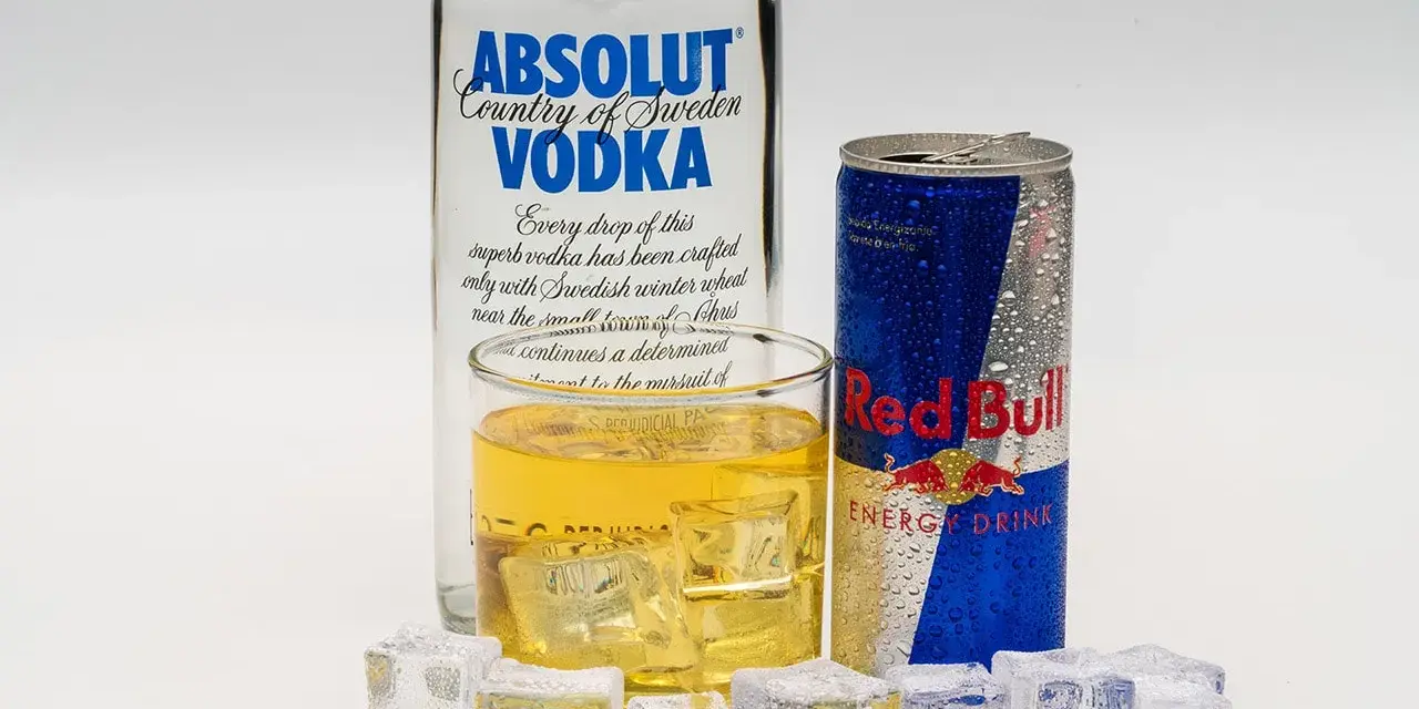 Szklanka z drinkiem, puszka Red Bulla i butelka wódki Absolut – klasyczny energetyk z alkoholem.