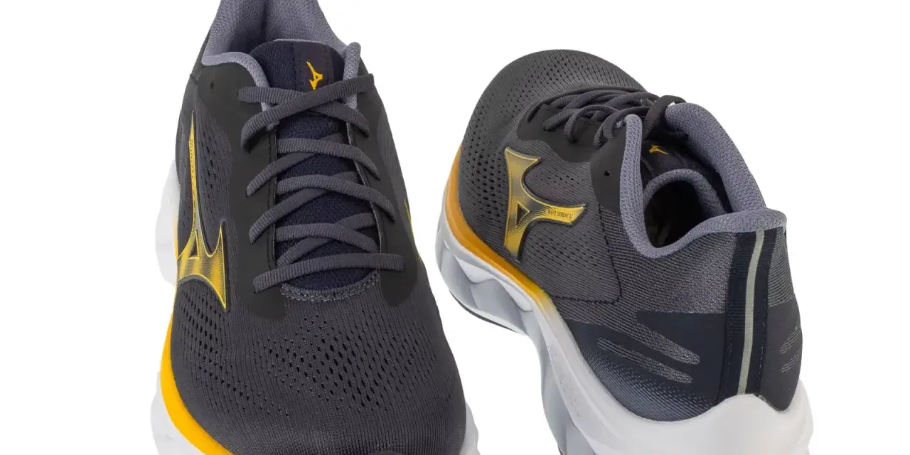 Dwa buty do biegania Mizuno w kolorze grafitowym z żółtymi akcentami. Mizuno to znana firma sportowa.
