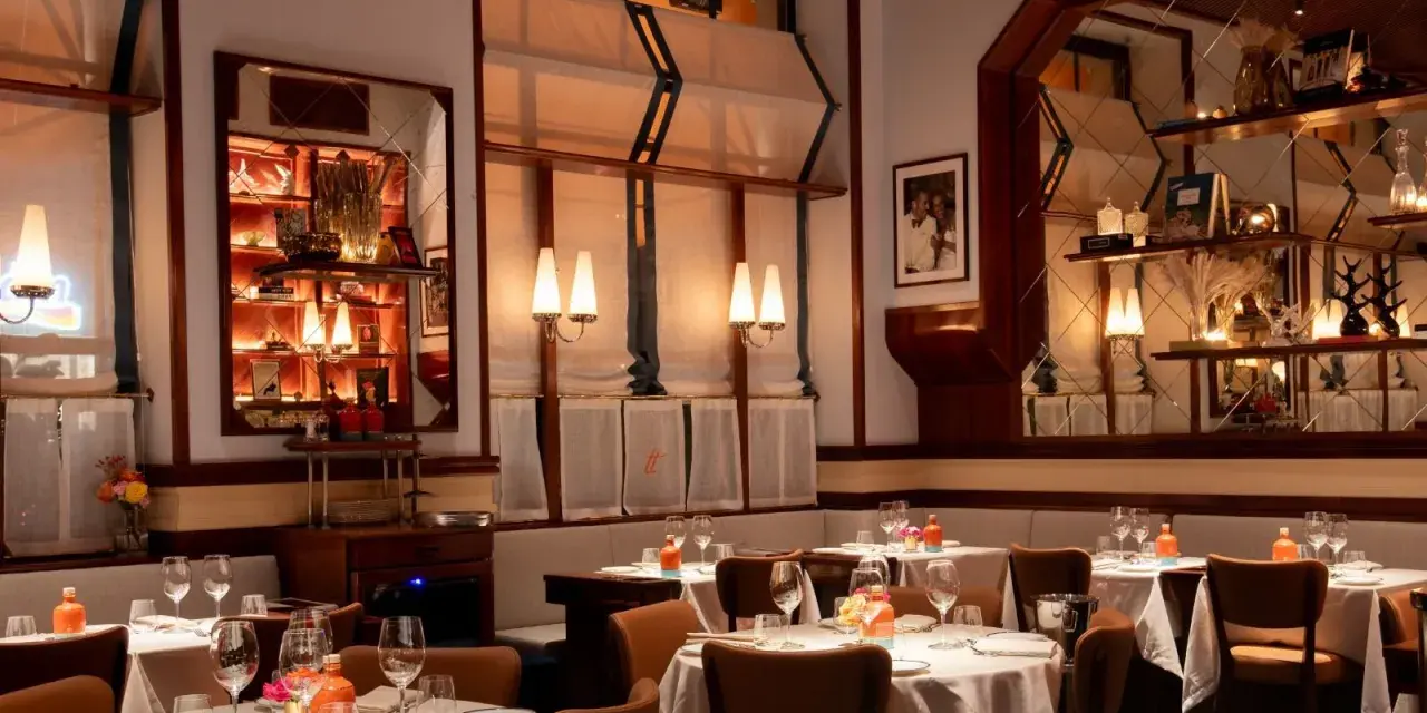 Tavoli apparecchiati in un ambiente elegante, ideale per scoprire i migliori ristoranti Milano. Luci soffuse e dettagli raffinati creano un'atmosfera accogliente.