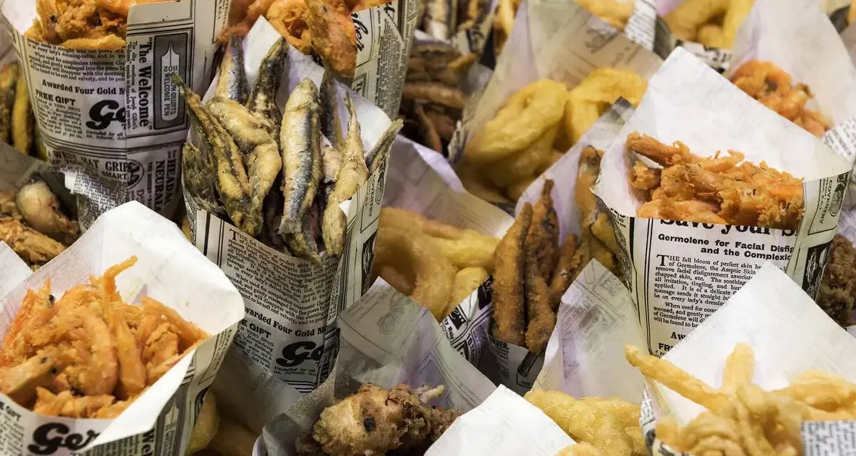 Una variedad de fritura de pescado, incluyendo camarones, boquerones y calamares, servidos en conos de papel.