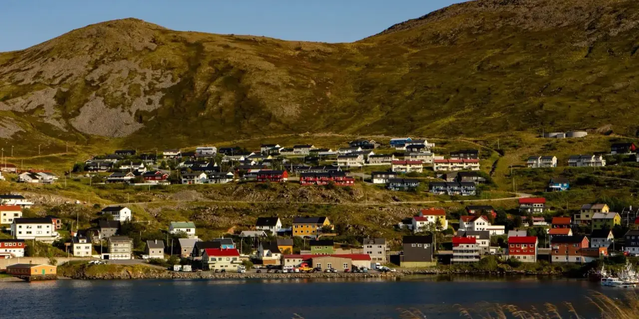 Kolorowe domy nad fiordem, w tle górzysty krajobraz. Nordcamp Norwegia, malownicza wioska rybacka.