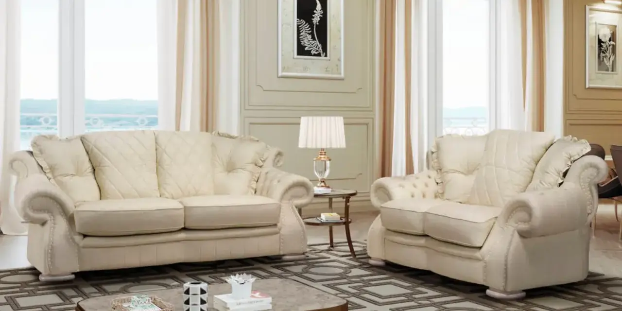 Elegante soggiorno con divani chiari, un tavolino e una lampada. Il tessuto sembra il miglior tessuto per divani antimacchia, ideale per una casa raffinata.