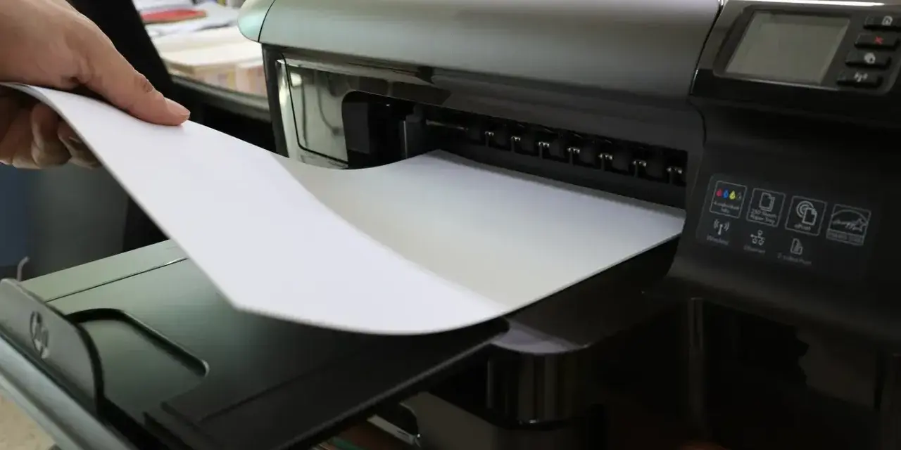 Dłoń wkłada papier do drukarki. To nie jest elementem eksploatacyjnym drukarki laserowej, lecz jej podstawowym materiałem.