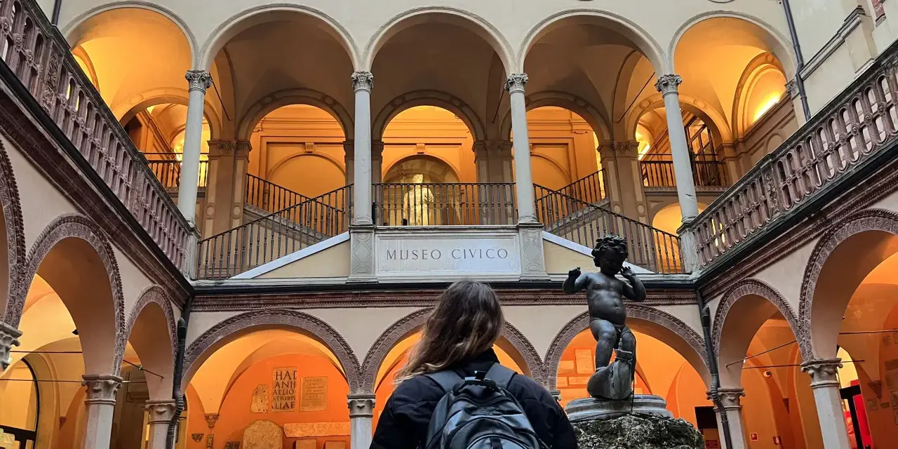 Cortile del Museo Civico, uno dei musei da visitare a Bologna, con una statua di putto e una persona con zaino.