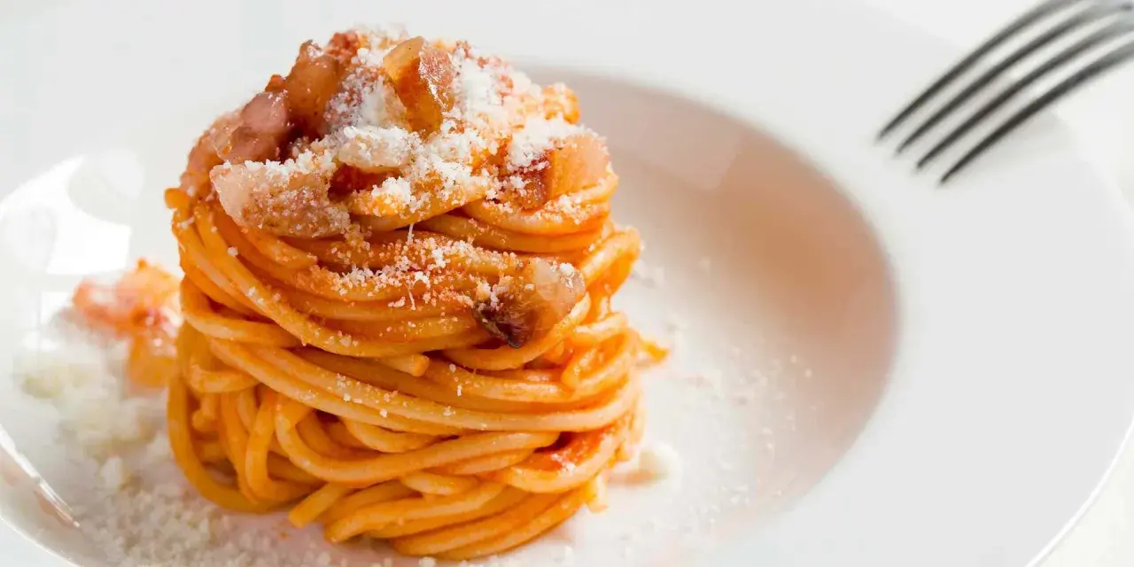 Un piatto di spaghetti alla amatriciana ricetta, conditi con guanciale croccante e pecorino grattugiato, pronti per essere gustati.