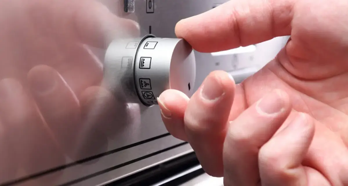 Ein Finger dreht am Drehregler, um die Heizart für den Backofen einzustellen. So funktioniert ein Backofen: Wahl der richtigen Funktion.