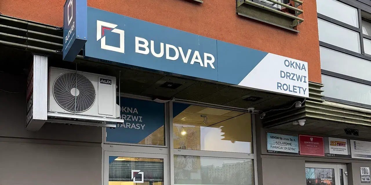 Logo i szyld salonu okien i drzwi "BUDVAR" z napisem "OKNA DRZWI ROLETY".
