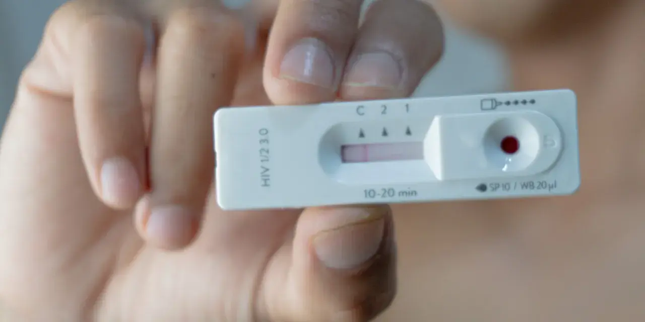 Dłoń trzyma test na HIV z widocznym wynikiem.