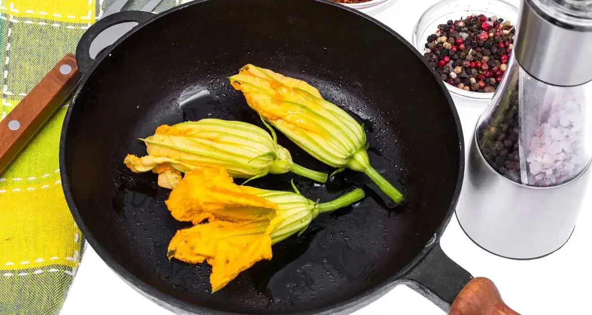 Fiori di zucca in padella, pronti per essere impanati e fritti. Accanto, spezie e sale per insaporire.