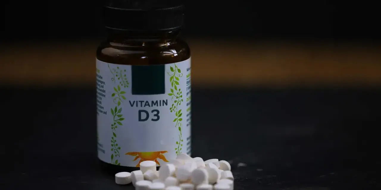 Flasche mit Vitamin D3 und Pillen. Wann einnehmen? Am besten mit einer Mahlzeit, um die Aufnahme zu verbessern.