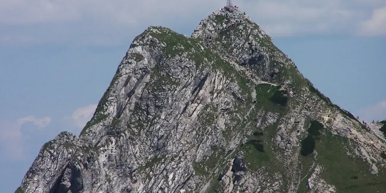 Szczyt Giewontu z krzyżem, pełen turystów. Czy Giewont jest trudny? Trasa wymaga kondycji, ale widoki wynagradzają wysiłek.