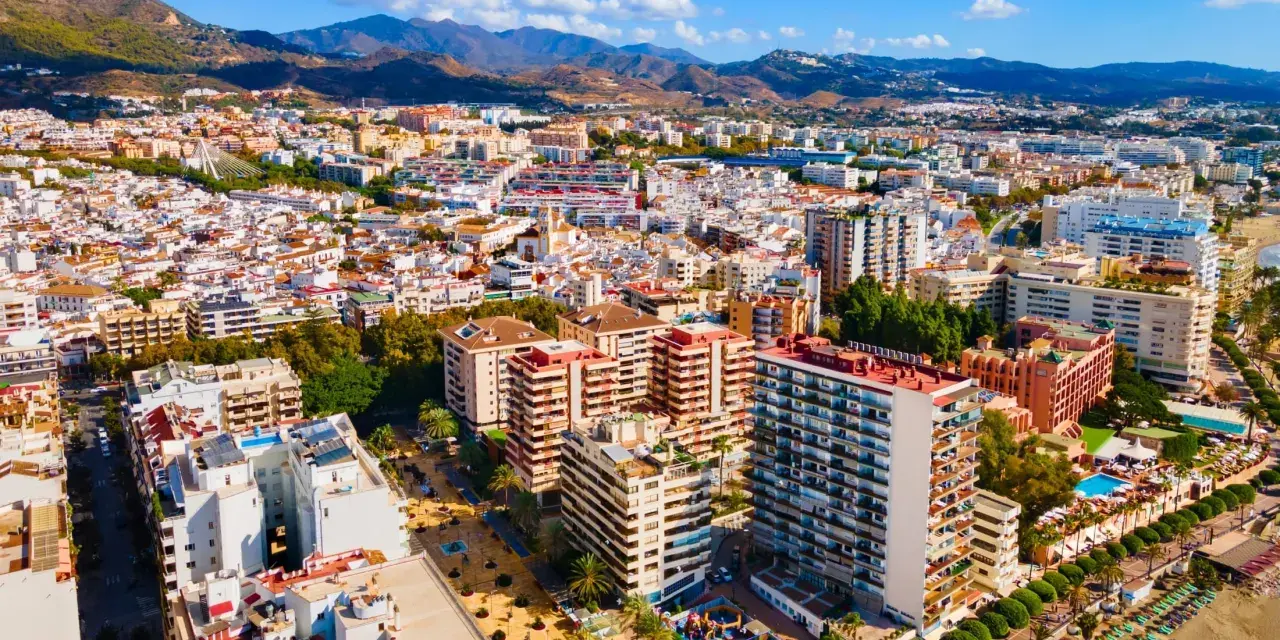 Widok z lotu ptaka na nadmorskie miasto Marbella, z górami w tle. Widać plażę, hotele i budynki mieszkalne.