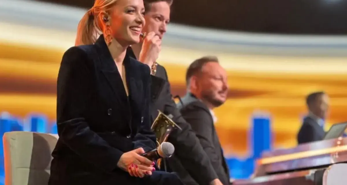 Uśmiechnięta wokalistka, która śpiewa w "Jaka to melodia", siedzi obok pianistów na scenie.