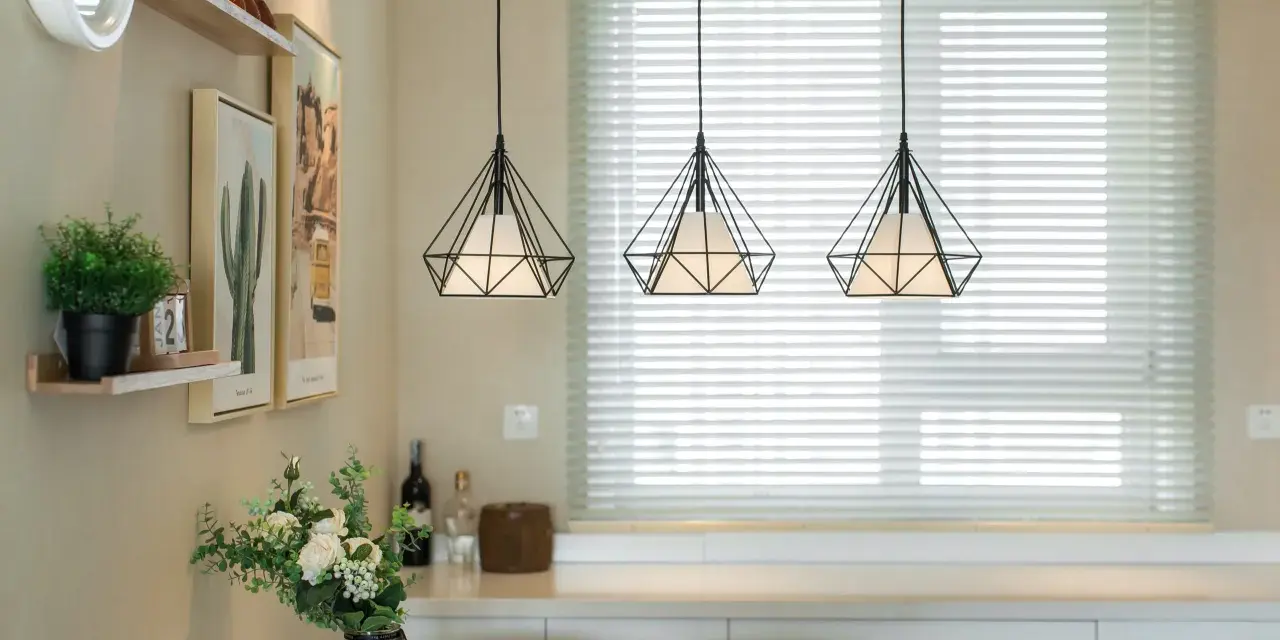 Trzy wiszące lampy w kształcie diamentu nad stołem w salonie.