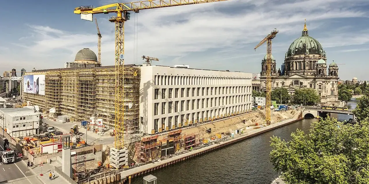 Baustelle am Berliner Dom, Kräne ragen in den Himmel. Ein neues Gebäude entsteht, während der Dom in seiner Pracht erstrahlt. Ein Blick auf das heutige Berlin, das sich ständig neu erfindet.