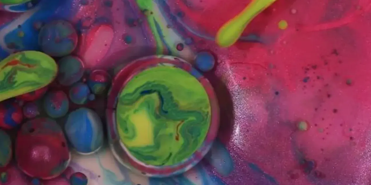 Peinture acrylique et liquide vaisselle créant des bulles colorées et des tourbillons abstraits, un univers visuel vibrant et mouvant.