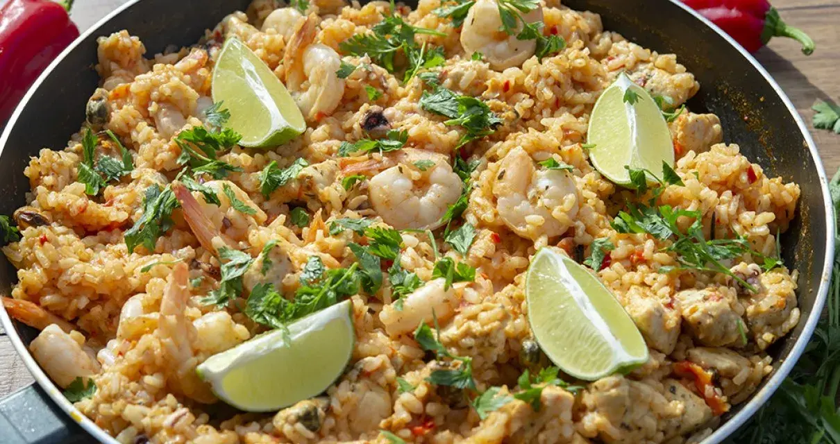 Pyszna paella z kurczakiem, krewetkami i limonką, posypana świeżą pietruszką. Idealna na letni obiad.