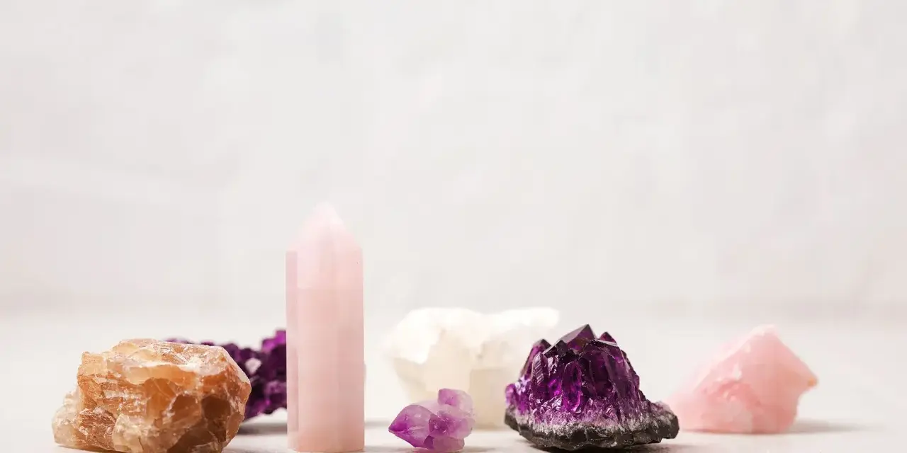 Colección de cristales energéticos: amatista, cuarzo rosa y calcita anaranjada, dispuestos sobre una superficie clara.