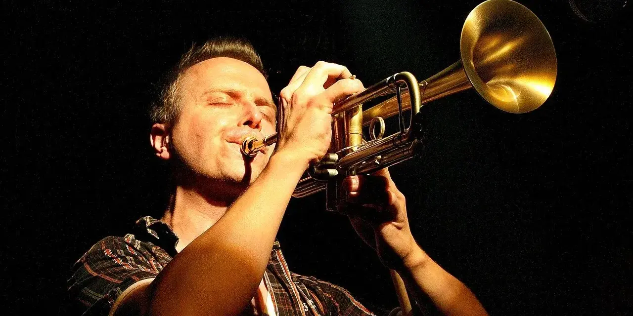 Muzyk gra na trąbce, zamykając oczy. Czy to synkopa co to? Muzyka jazzowa.