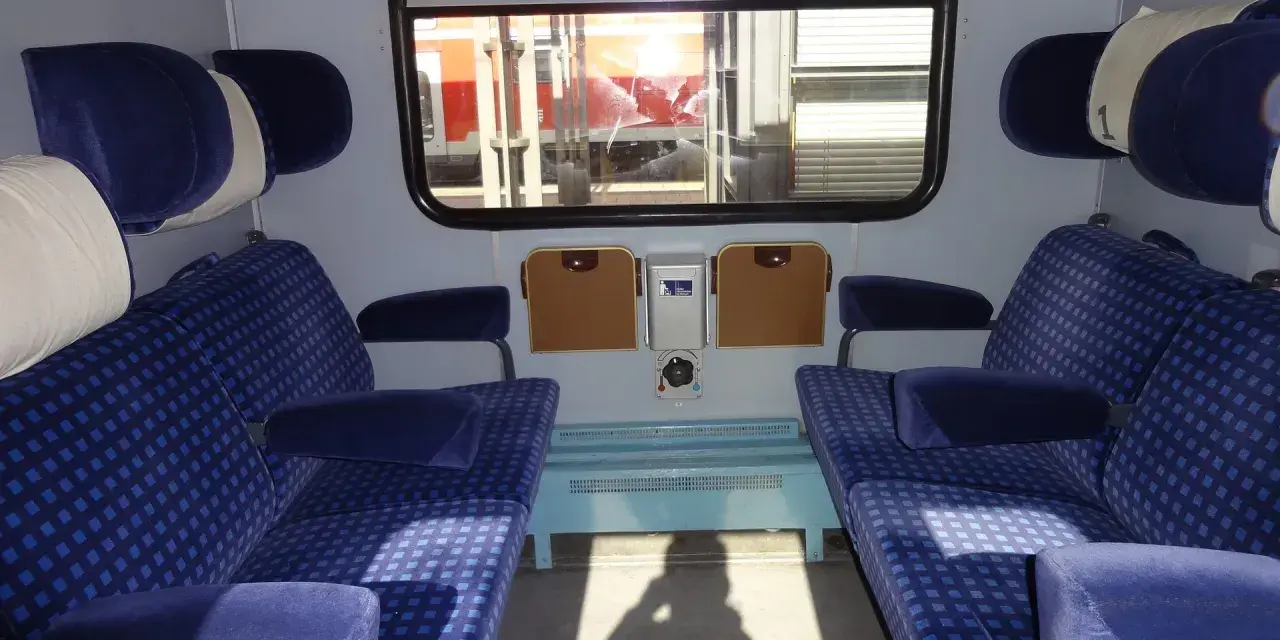 Wnętrze wagonu z niebieskimi siedzeniami w kratkę. Różne rodzaje wagonów oferują komfort podróży.