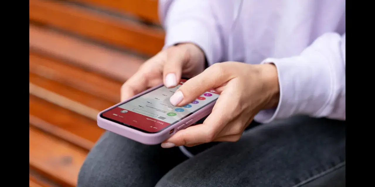 Dłonie kobiety obsługują smartfon, czując subtelne wibracje haptyczne przy każdym dotknięciu ekranu.