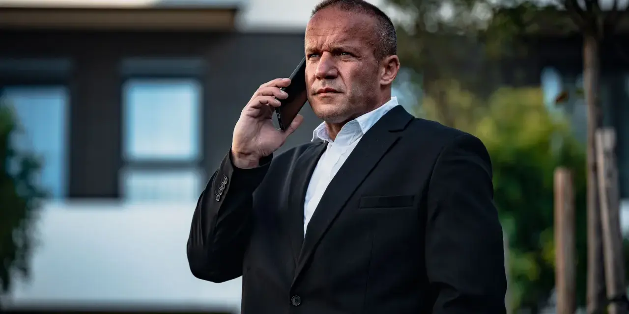 Krzysztof Bukowski, reżyser, w garniturze rozmawia przez telefon.