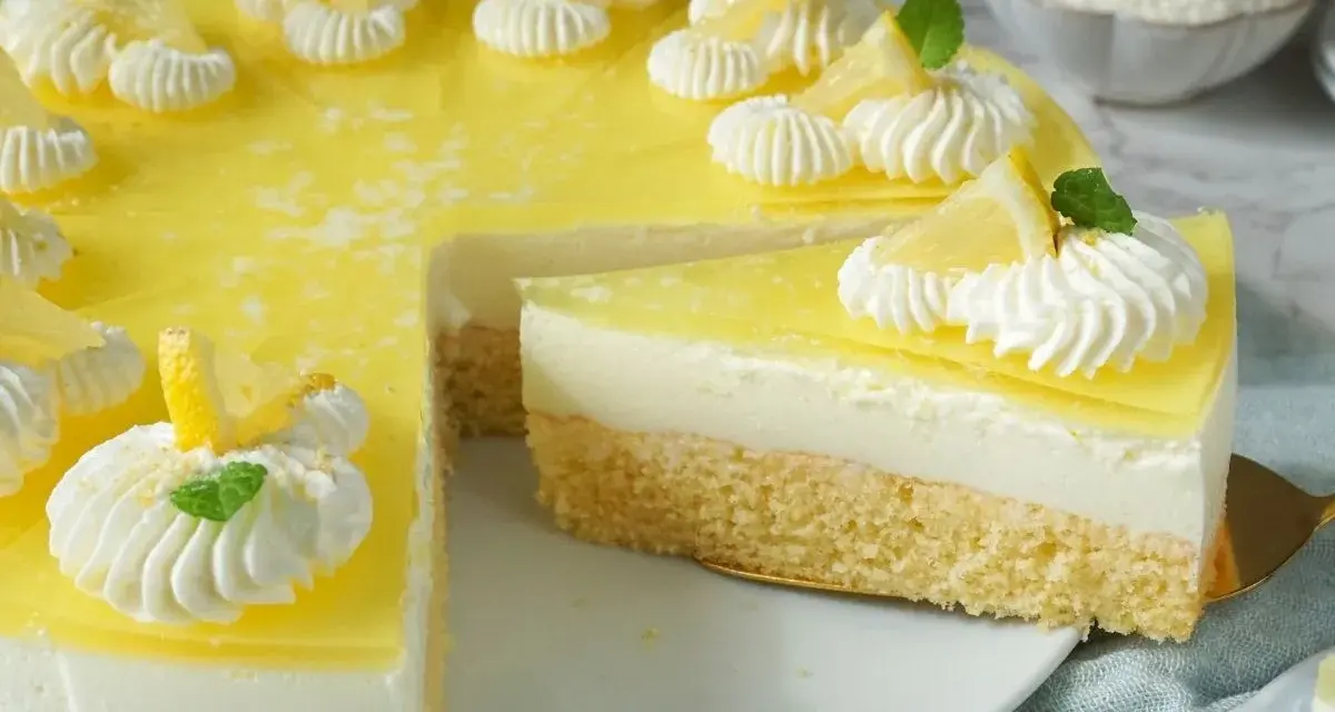 Erfrischende joghurt-torte mit biskuitboden, dekoriert mit Zitronenspalten und Sahnetupfern.