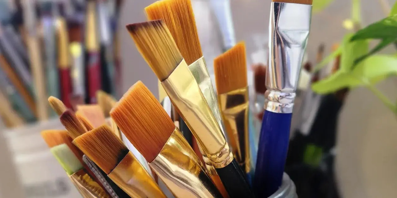 Un pot rempli de pinceaux aux poils orangés, prêts à être utilisés avec un nettoyant peinture acrylique.