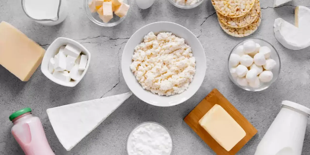Różnorodne produkty bogate w wapń: mleko, sery, jogurt, masło, jajko i wafle ryżowe.