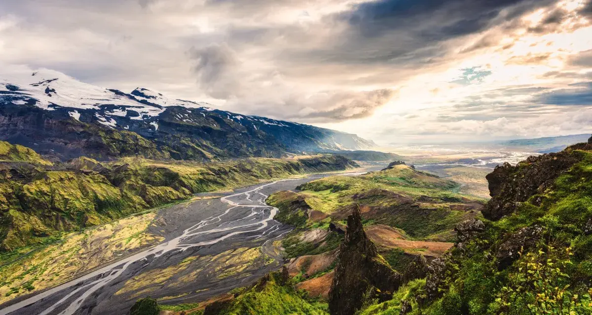 Spektakularny krajobraz Islandii z rzeką i ośnieżonymi górami. Warto zobaczyć, choć islandia ceny mogą być wysokie.
