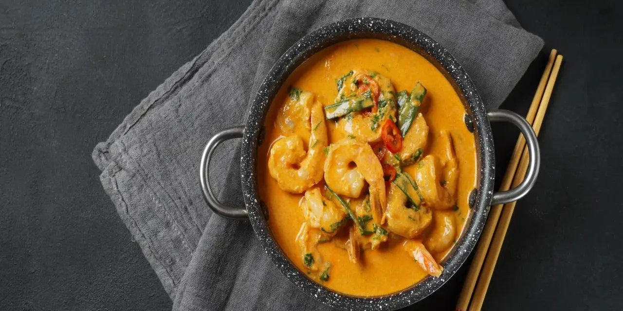 Aksamitne tajskie curry z krewetkami, podane w garnuszku z pałeczkami.