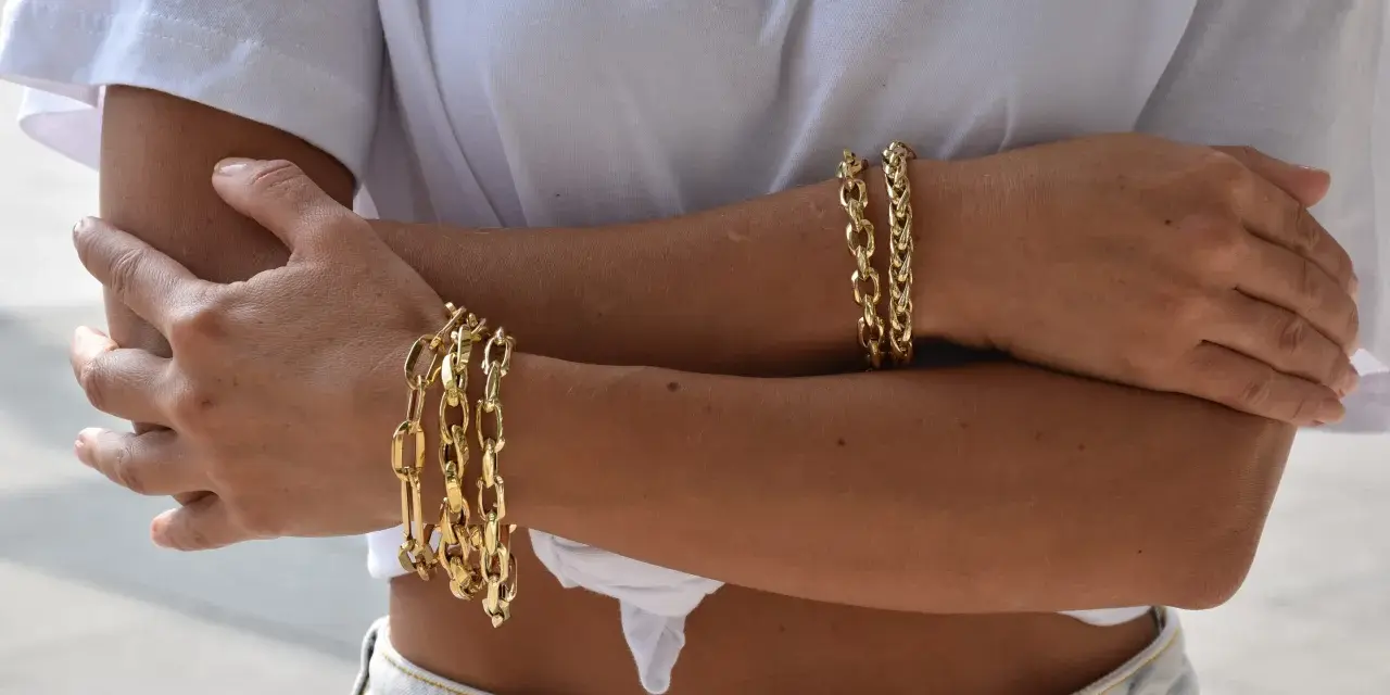 Bracciali in oro 18 carati, più brillanti e preziosi rispetto all'oro 9 carati, adornano le braccia di una donna.