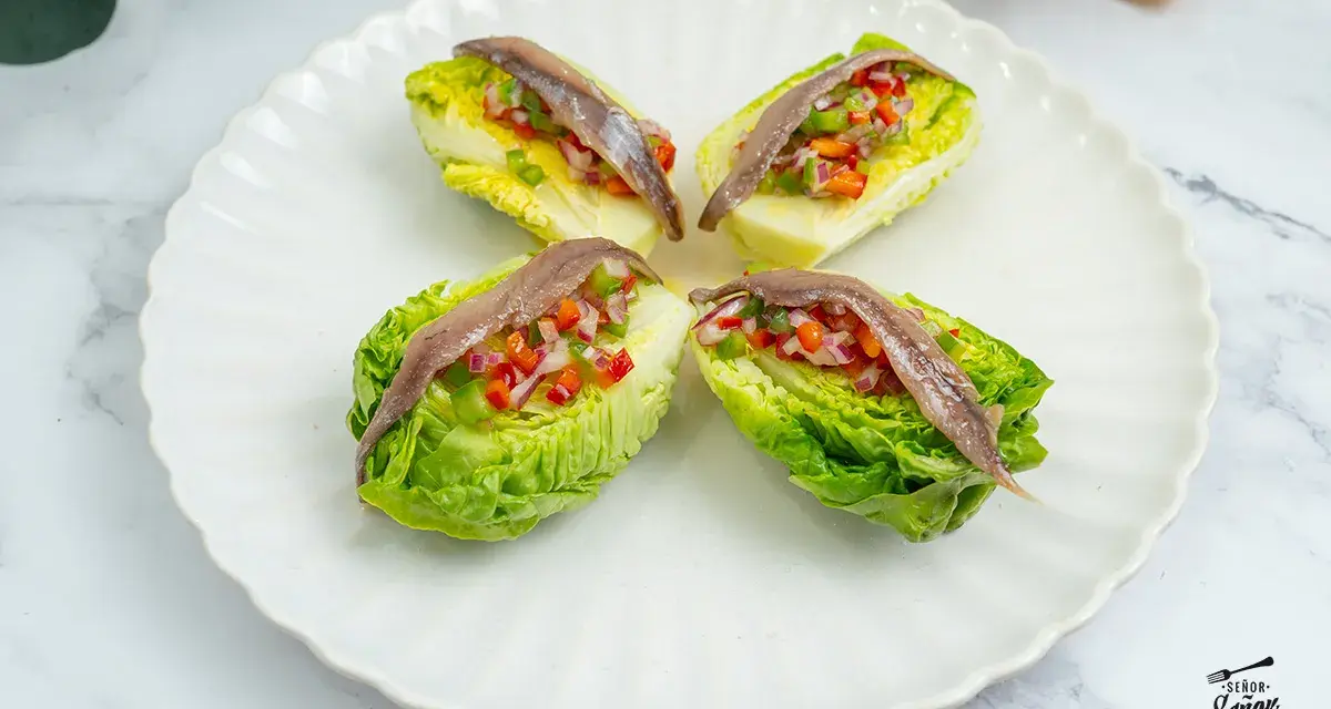 Cuatro cogollos de Tudela rellenos de pimientos y cebolla, coronados con anchoas. Frescura y sabor en cada bocado.
