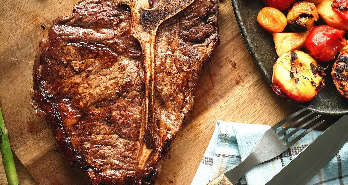 Un succulent côte de bœuf grillé, accompagné d'asperges et de tomates rôties, prêt à être dégusté.