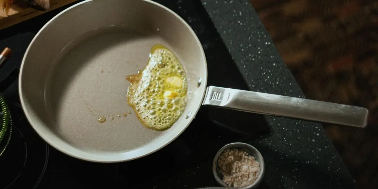 Butter schmilzt in einer beschichteten Pfanne, bereit für Fisch. Die Pfanne ist leicht zu reinigen.