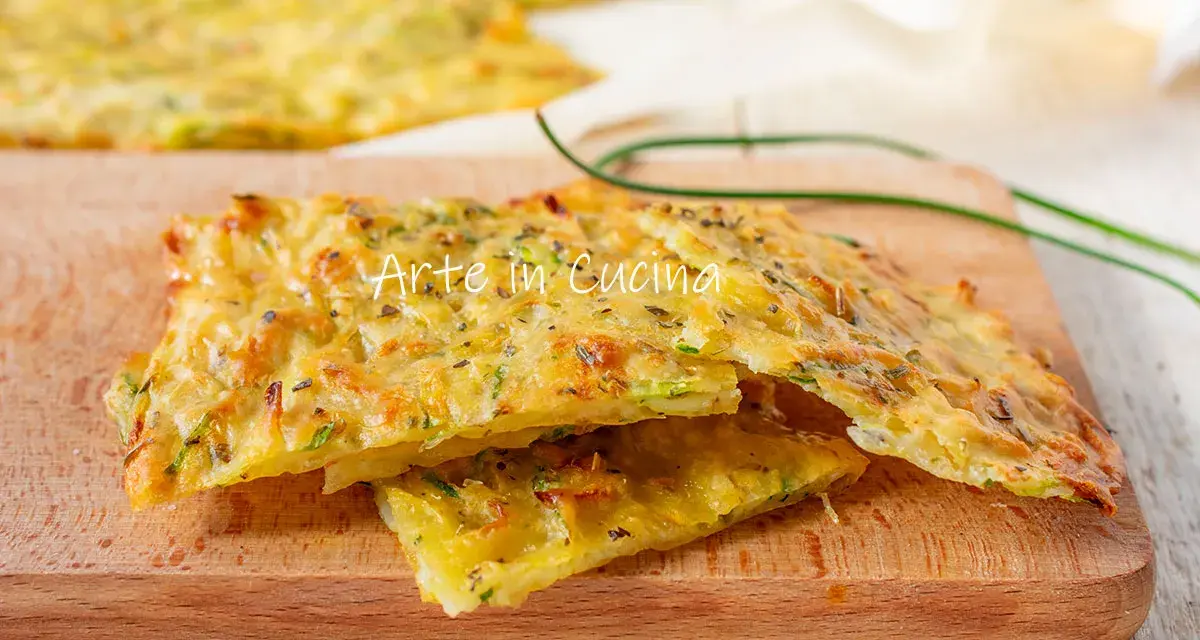Schiacciata di zucchine dorata e croccante, con erbe aromatiche, servita su un tagliere di legno.