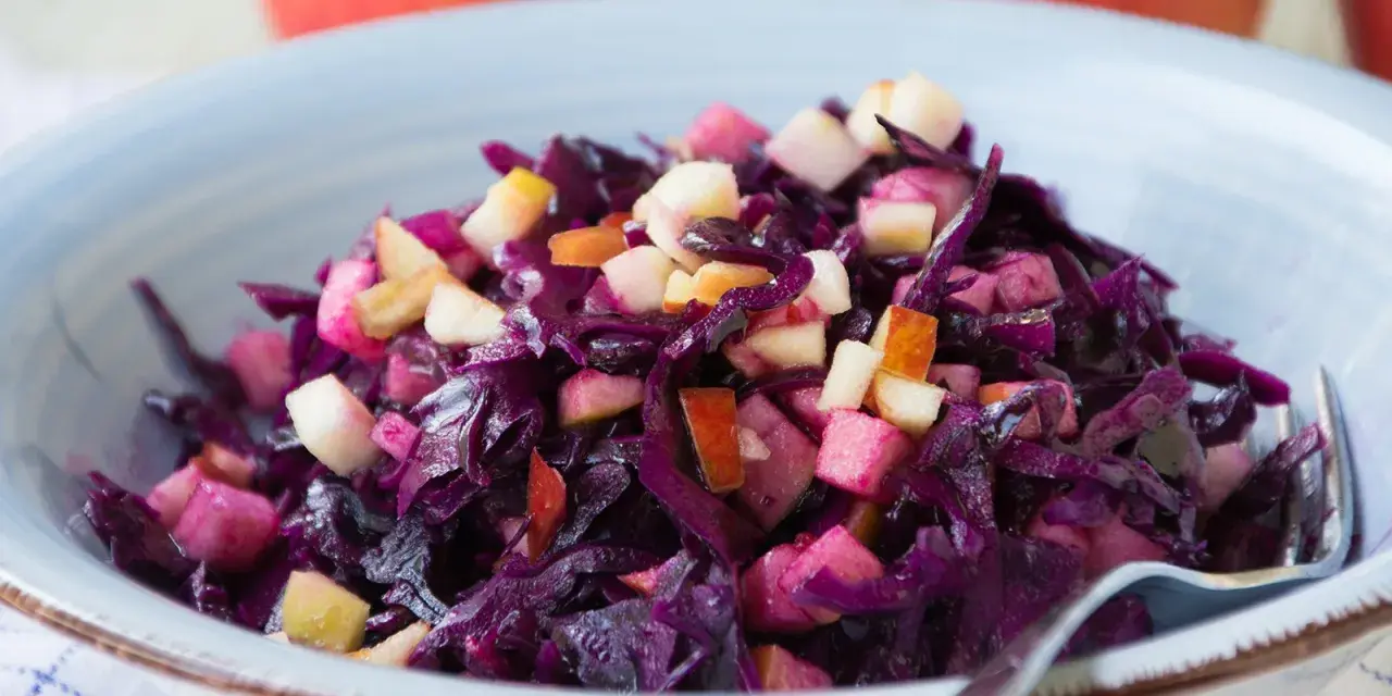 Schüssel mit leckerem rotkohl salat, garniert mit Apfelstücken.