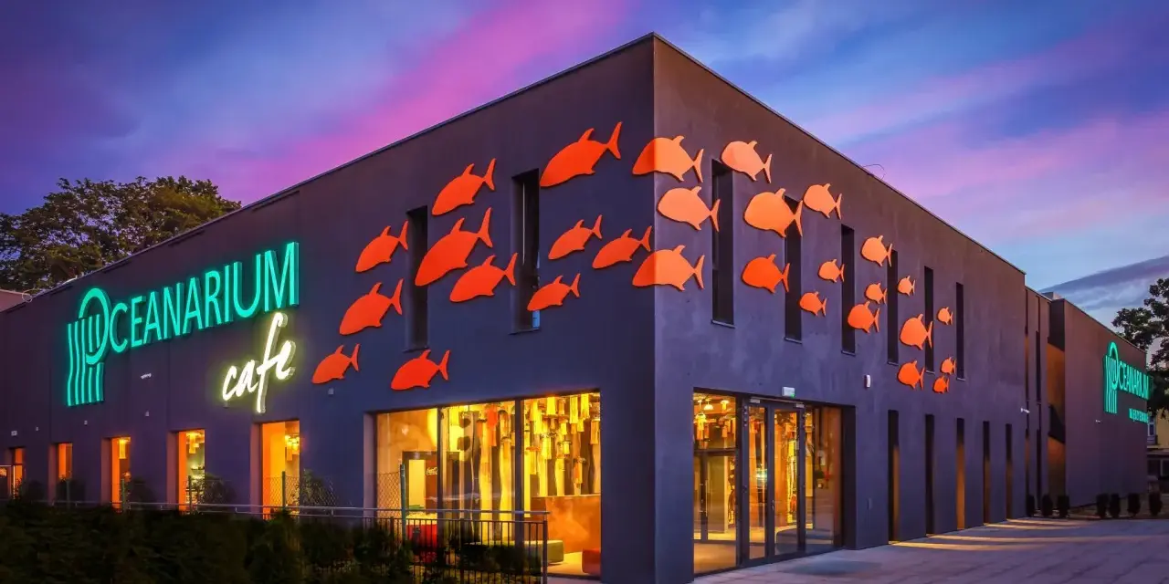 Oceanarium w Międzyzdrojach, jedna z głównych atrakcji, z neonowym napisem i pomarańczowymi rybkami na fasadzie.