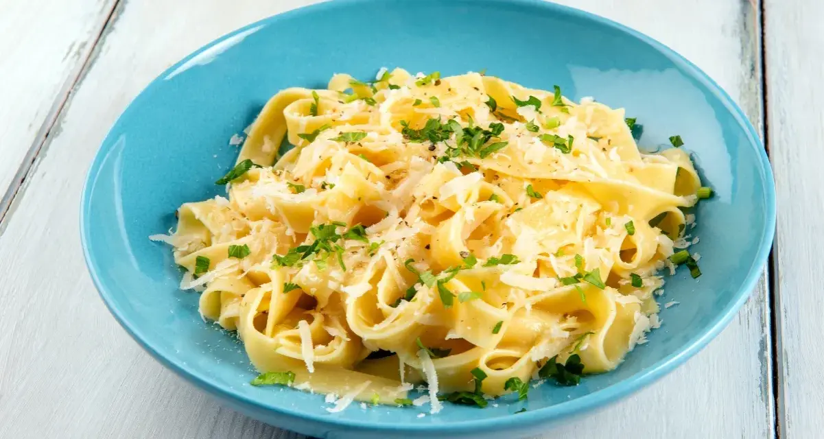 Fettuccine al burro e parmigiano, uno dei sughi per pasta più semplici e gustosi, guarnito con prezzemolo fresco.