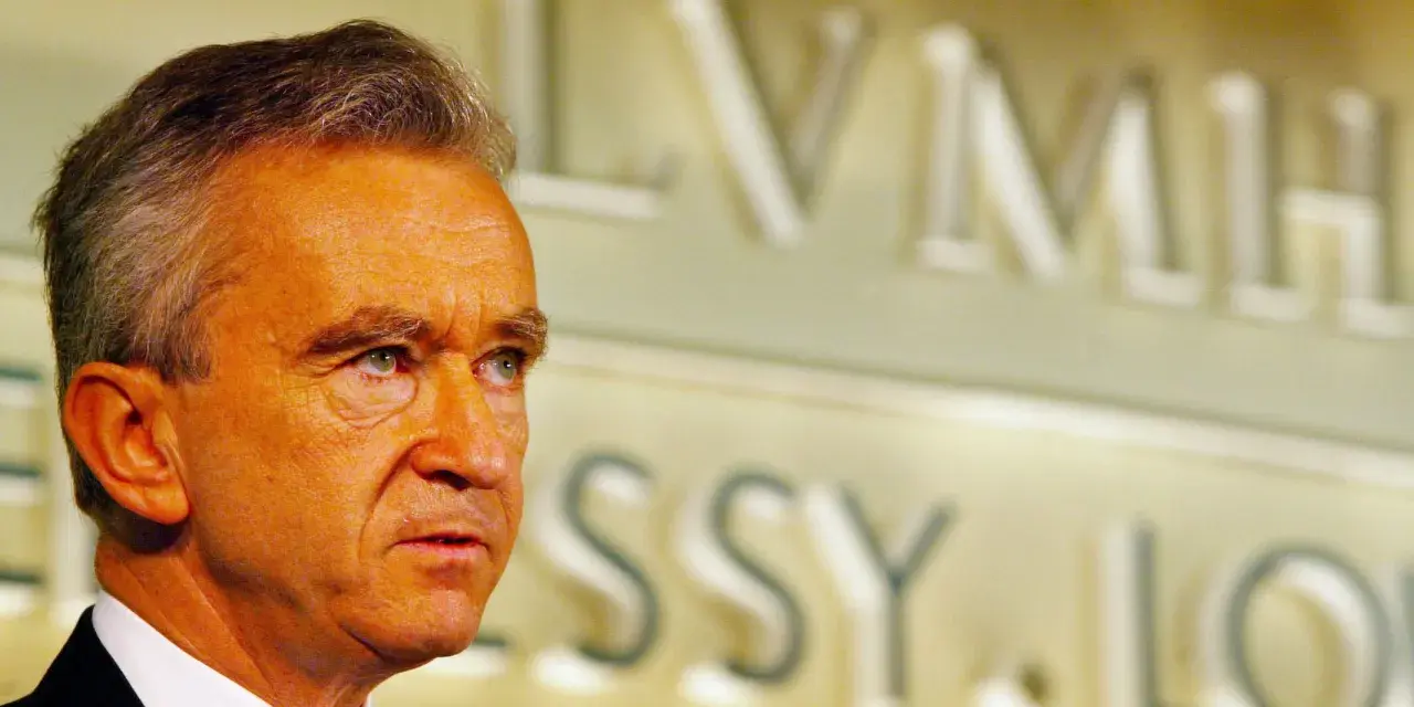 Bernard Arnault, proprietario Dior, guarda pensieroso. Sullo sfondo, il logo LVMH.