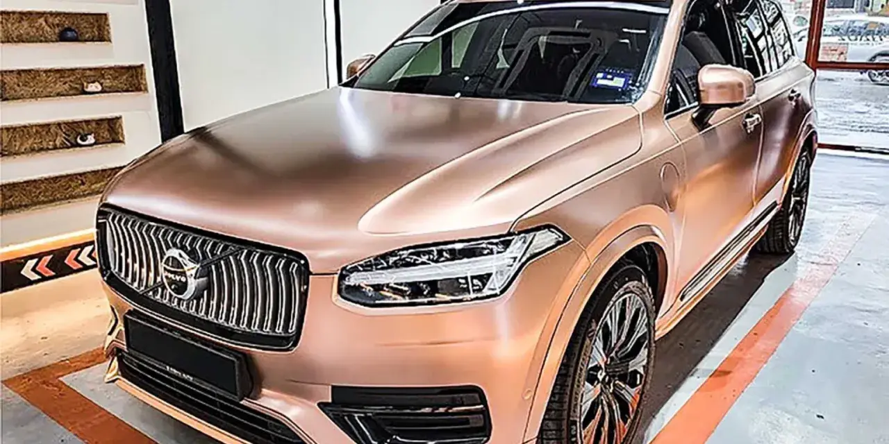 En lyxig Volvo XC90 med en glänsande roséguld folierad bil. Bilen står i ett garage med orange linjer på golvet.