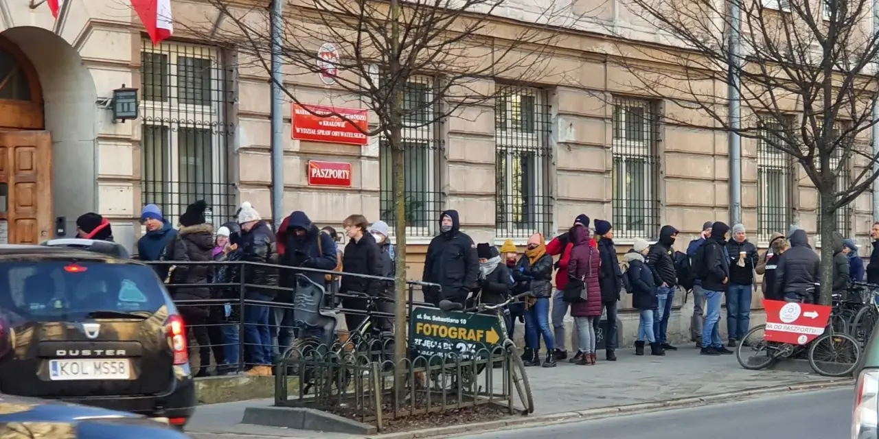 Kolejka do odbioru paszportu w Krakowie. Ludzie stoją przed budynkiem urzędu.